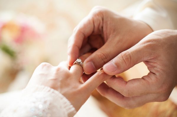 A man places a wedding ring on his bride's finger.