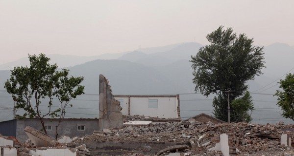 Demolition of houses with mountains and a few trees left standing.