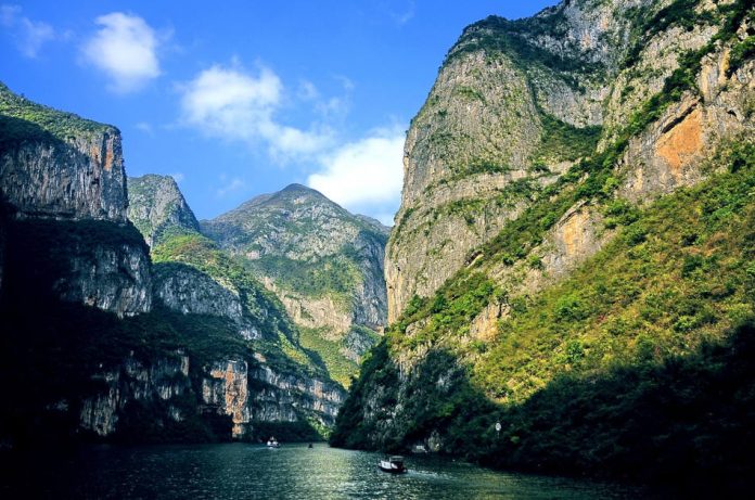 Mountains can be seen along the banks as boats travel down the Yangtze River in China