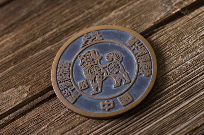 Dog animal zodiac sign in a coin on top of the wood background.