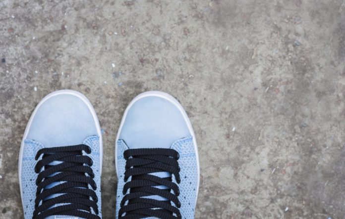 Sneakers of blue suede with black laces on the sidewalk.