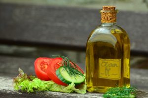 A bottle of olive oil and salad ingredients.