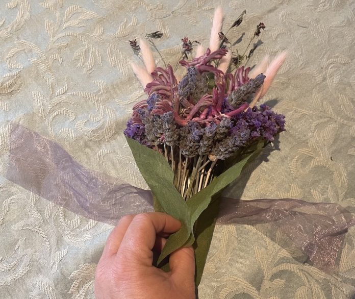 ribbon being tied to bouquet of dry flowers