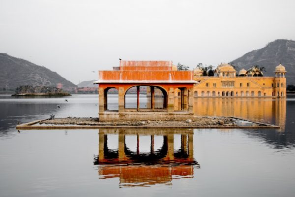 orange water palace in India reflecting off water on an overcast day
