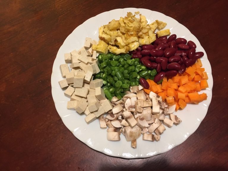 tofu, mushroom, carrot, beans, egg, kidney beans chopped on a plate