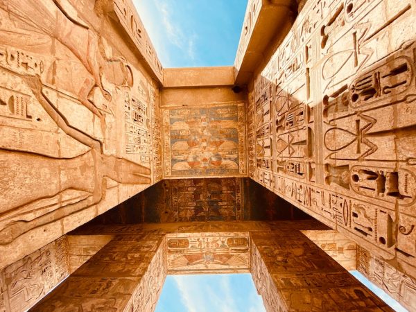 The Theban Necropolis in Egypt large stone orange sandstone structures with Egyptian painting and writing carved on the ceiling and walls