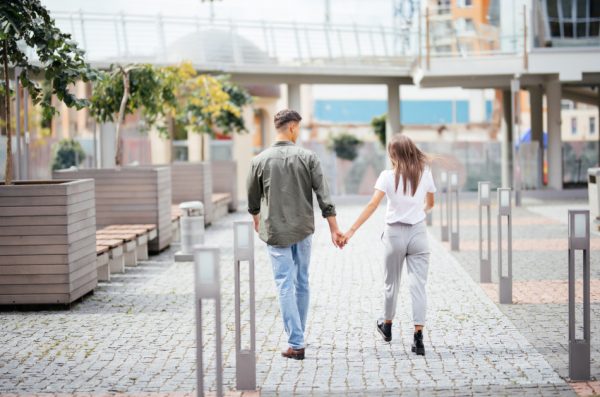 A young couple holding hands and walking together in the city.