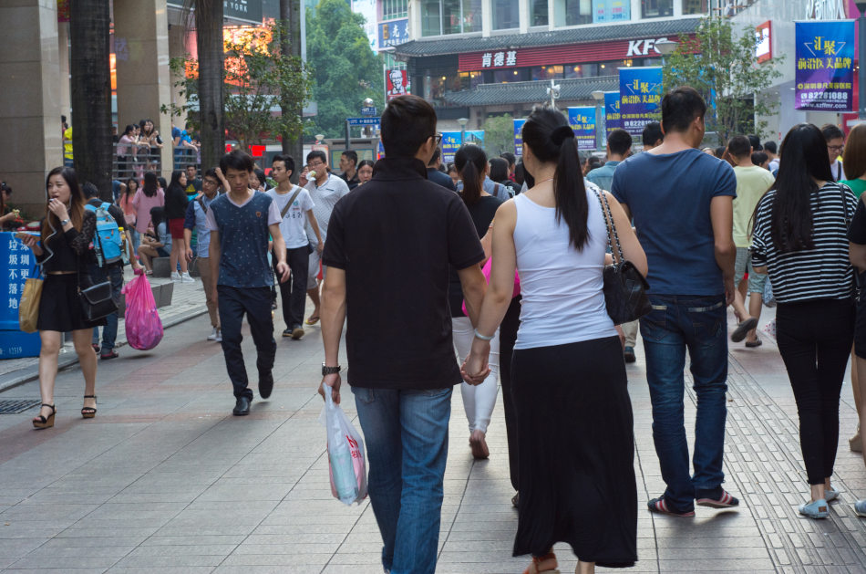 Couple walking hand in hand in a crowded shopping street in China.