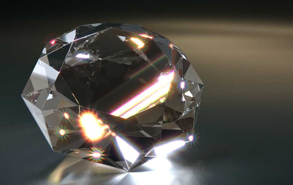 A diamond sits on a dark surface with light refracting off it.