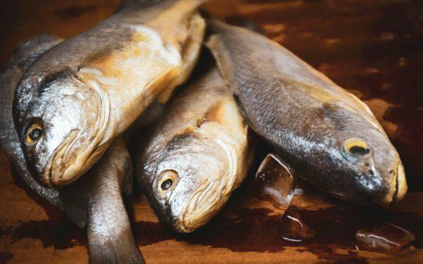 Raw fish sitting on a wooden surface.