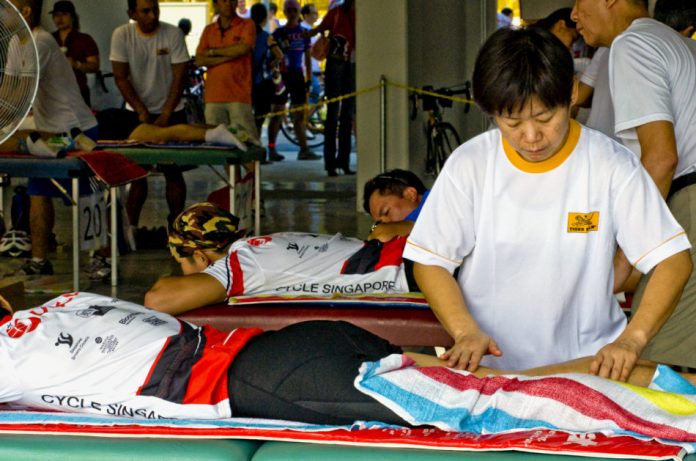 Cyclists receive a Tiger Balm massage on their legs after a race.