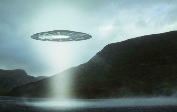 Artist's rendering of a UFO hovering over a mountain lake with a light beam coming down.