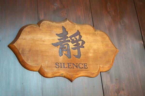 Wooden sign asking for silence in both English and Chinese script.
