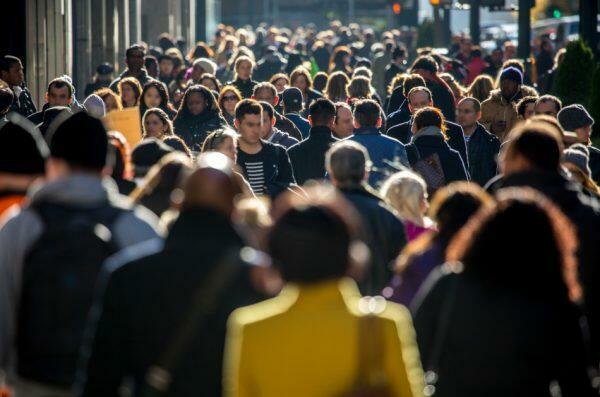 A crowd of people walking on a city sidewalk.