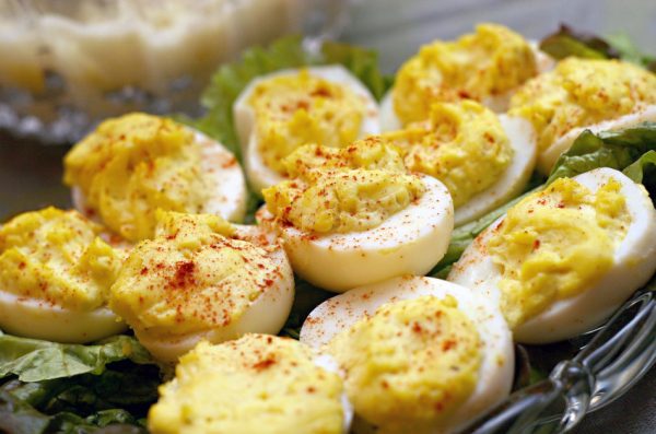 Deviled eggs sitting on a bed of lettuce in a crystal serving dish.