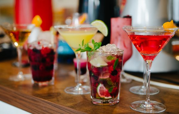 Various colorful cocktails sitting on a counter.