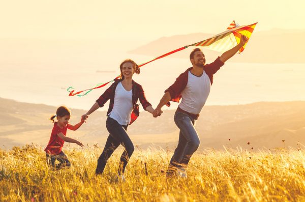 Happy family: father, mother, and daughter, run hand in hand with a kite.