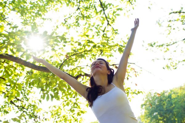 Young girl spreading hands with joy facing the sun.