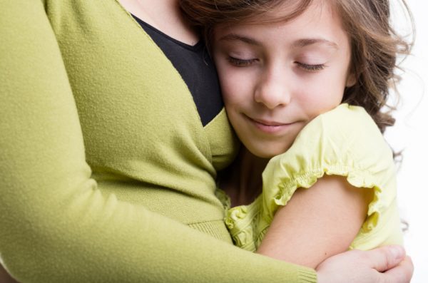 Daughter wrapped up in her mother's arms.