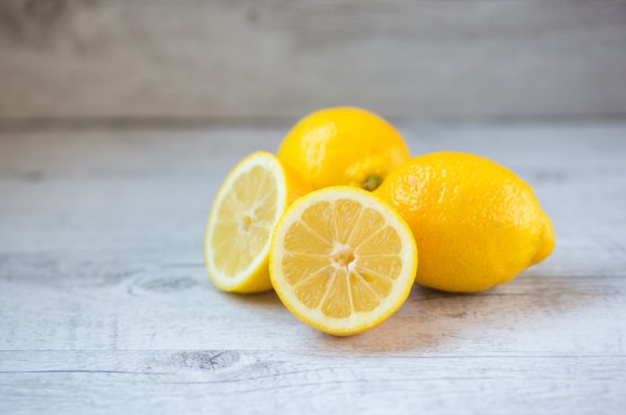 Three lemons sit on a wooden surface.