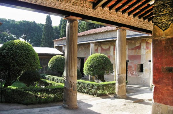 The ruins of a Pompeii Roman house with columns and a garden.