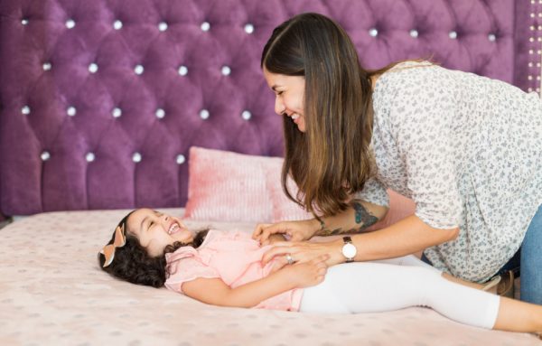 A happy mother tickling her daughter.
