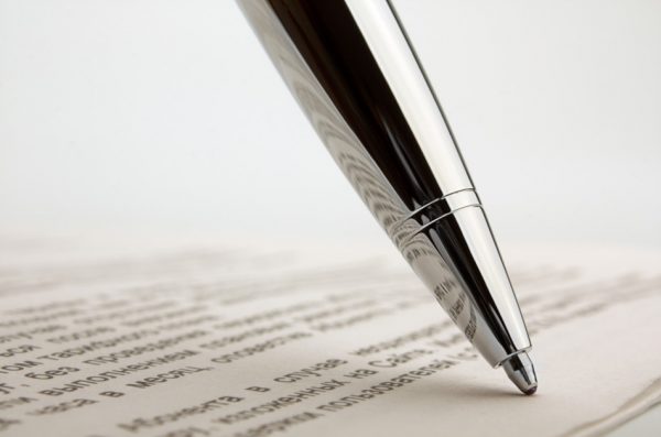 Shiny silver ballpoint pen on a contract, focusing on the reflection from the pen.
