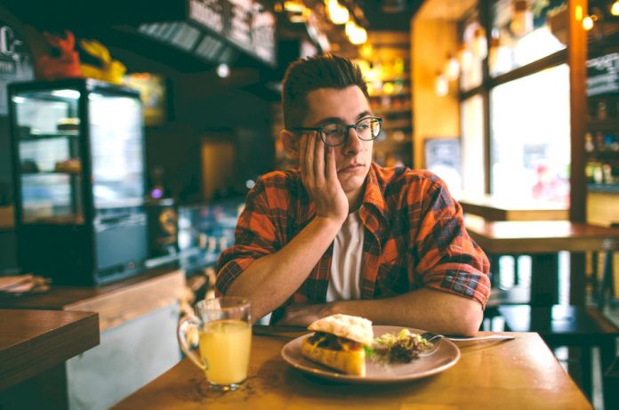 An unhappy man dines alone in a restaurant.