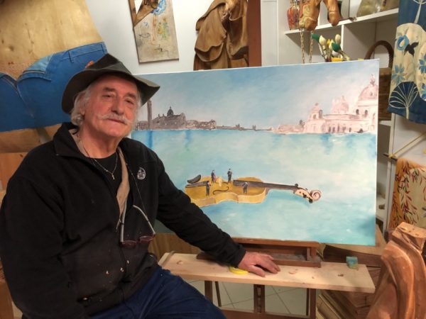 Photo of Livio de Marchi in front of a painting of 'Noah's Violin'.