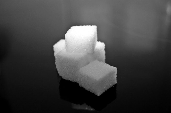 Sugar cubes sit on a dark background.