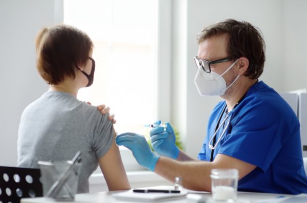 A man swabs a woman's arm in preparation for administering a shot.