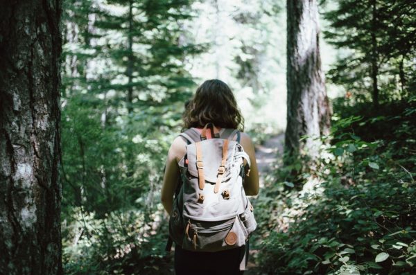 Woman wearing a backpack hiking through the forest.