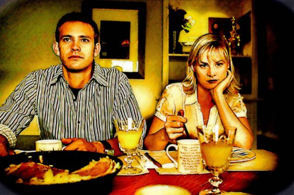 Unhappy young couple sitting next to each other at the breakfast table.