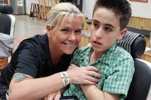 Australian barber Lisa Ann McKenzie poses in her barbershop with her customer, an autistic boy named Jordie.