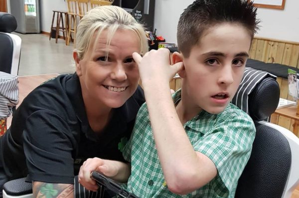 Australian barber Lisa Ann McKenzie poses in her barbershop with her customer, an autistic boy named Jordie.