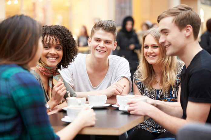 Group of young friends meeting in a cafe, sitting and chatting over their drinks.