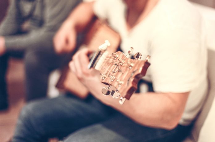 Young man strumming a guitar.