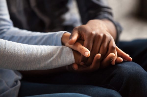 Closeup of the clasped hands of an African American couple.