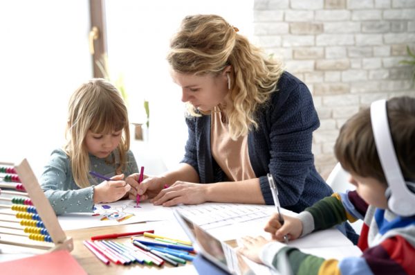 Mother helping her kids with homeschooling during the lockdown.