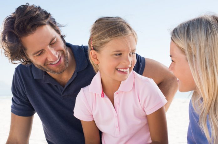 Little girl in conversation with her parents outdoors.