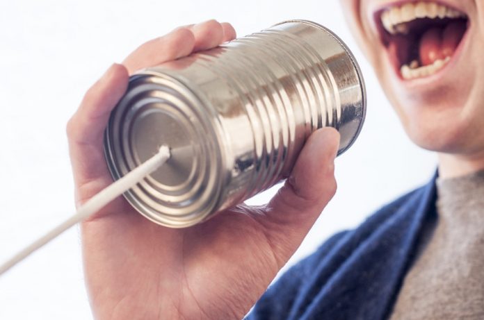 Young man talking into a "phone" made from a tin can and a string.