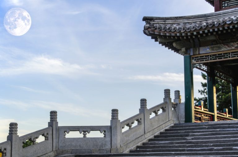 Asian pagoda seen along with the full moon in the sky.