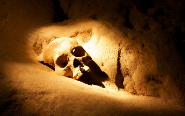 A human skull on the floor of a cave.