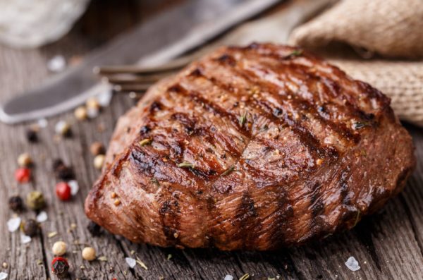Delicious grilled beef steak on a wooden board with spices.