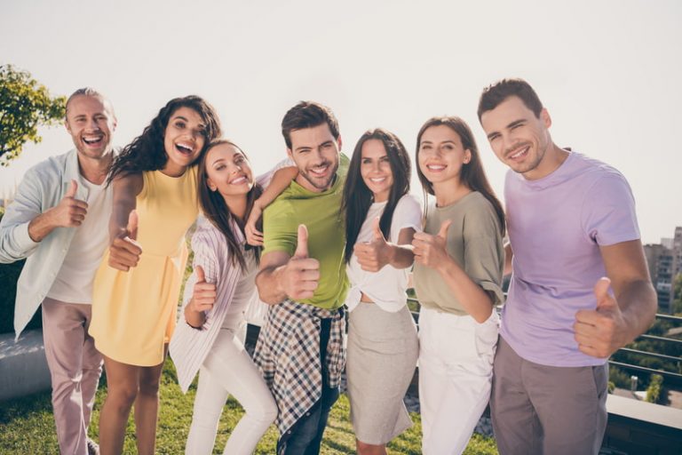 A group of young people smiling for the camera and giving thumbs-up.