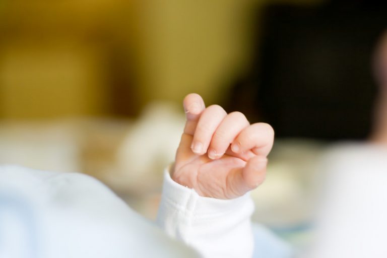 Close up of a tiny newborn infant's hand.