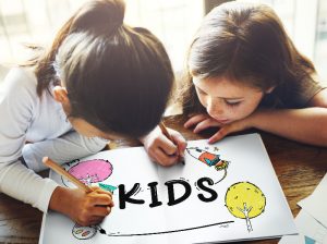 Two girls sitting at a wooden table and coloring together.