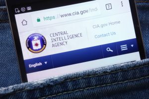 A mobile phone open to the CIA's homepage is sticking out of the pocket of a pair of blue jeans.