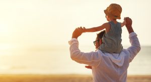 A dad with a daughter on his shoulders.