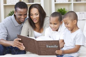 A family sitting together looking at a family photo album.